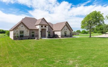 exterior shot of a home for sale with a nicely maintained front lawn with a tree and blue cloudy skies